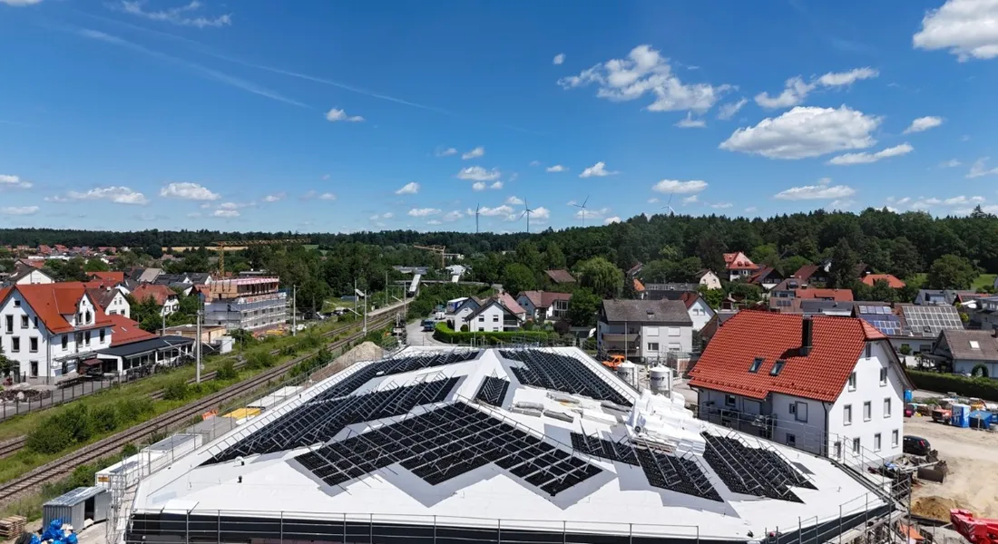 Große PV-Anlage auf einem Neubau im Ort, Luftaufnahme