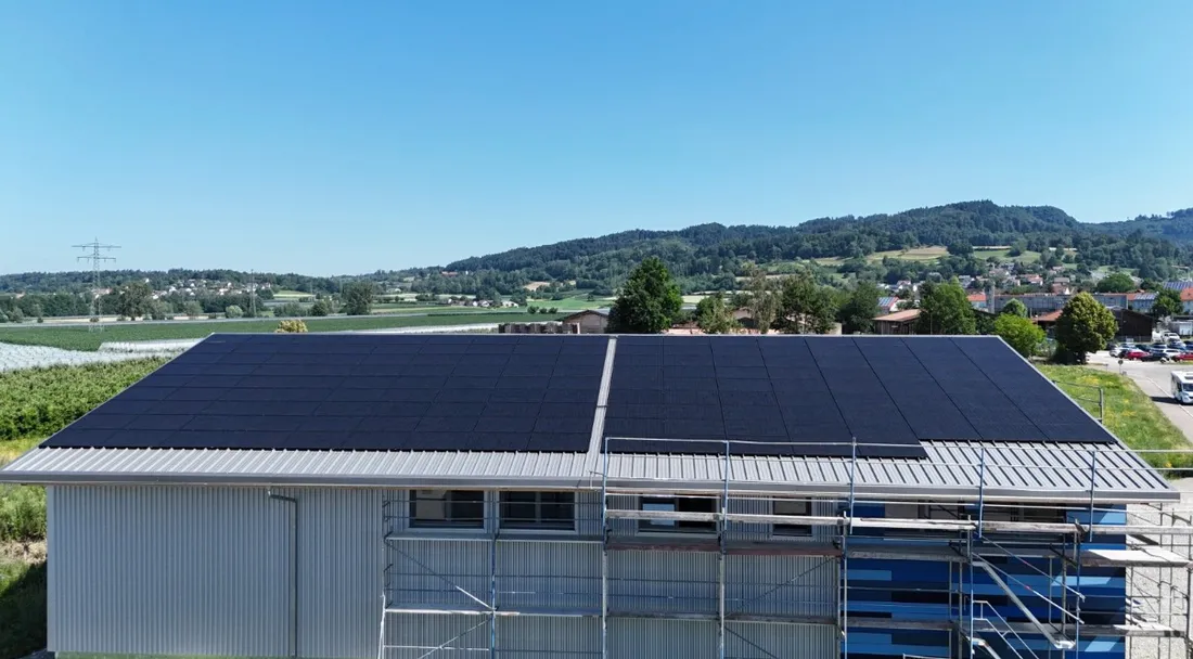 PV-Anlage auf einem Hallendach vor Bergpanorama