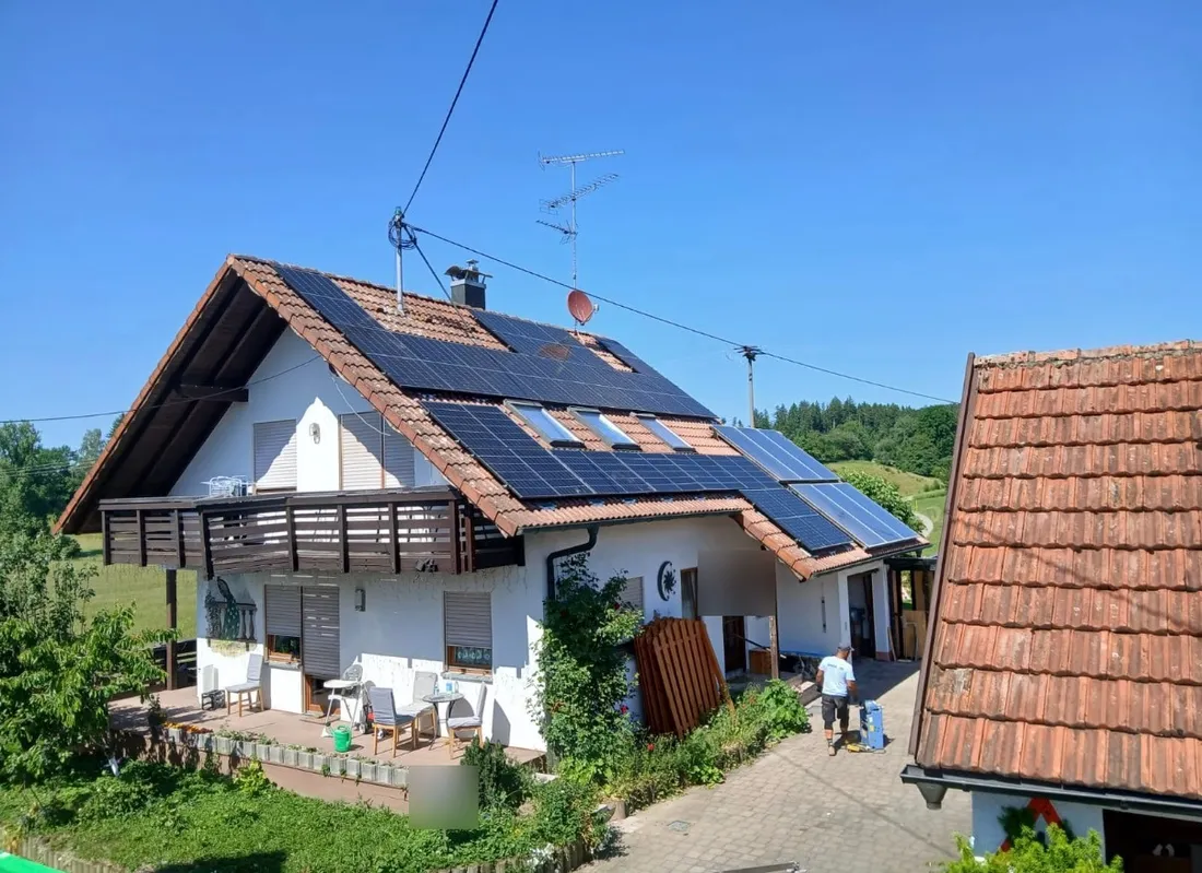 Photovoltaik auf einem Einfamilienhaus im Grünen, Monteur bei der Arbeit